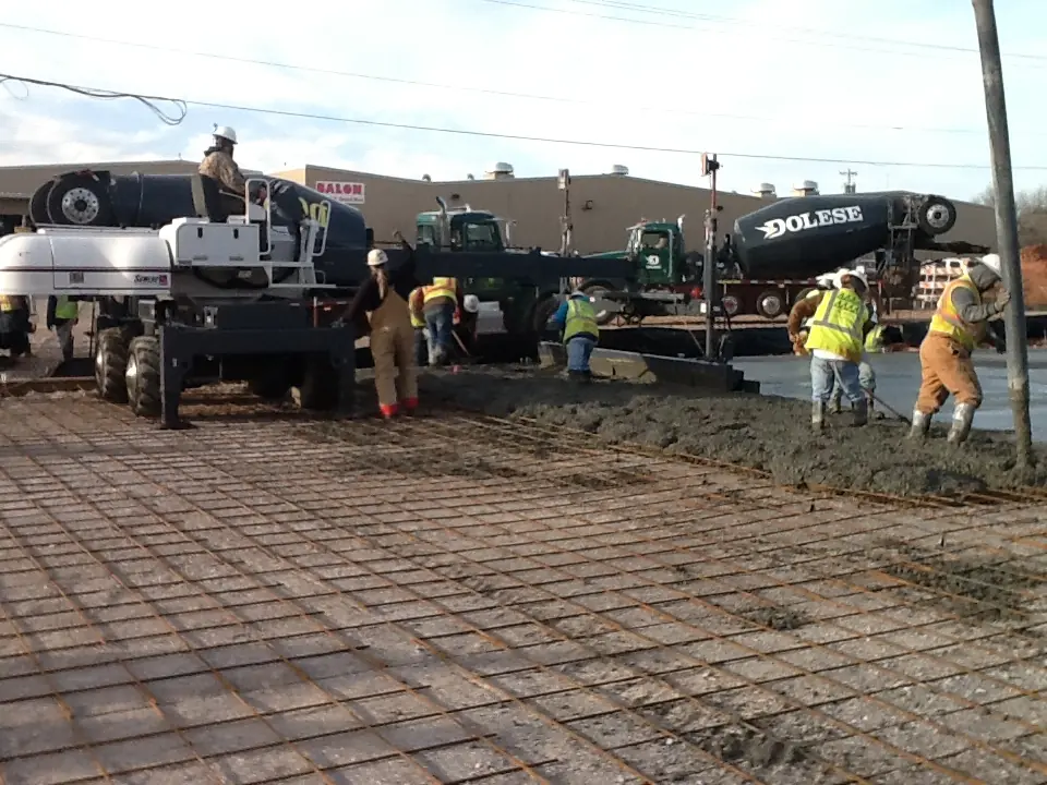 CEI crew placing concrete with a screed on a commercial jobsite