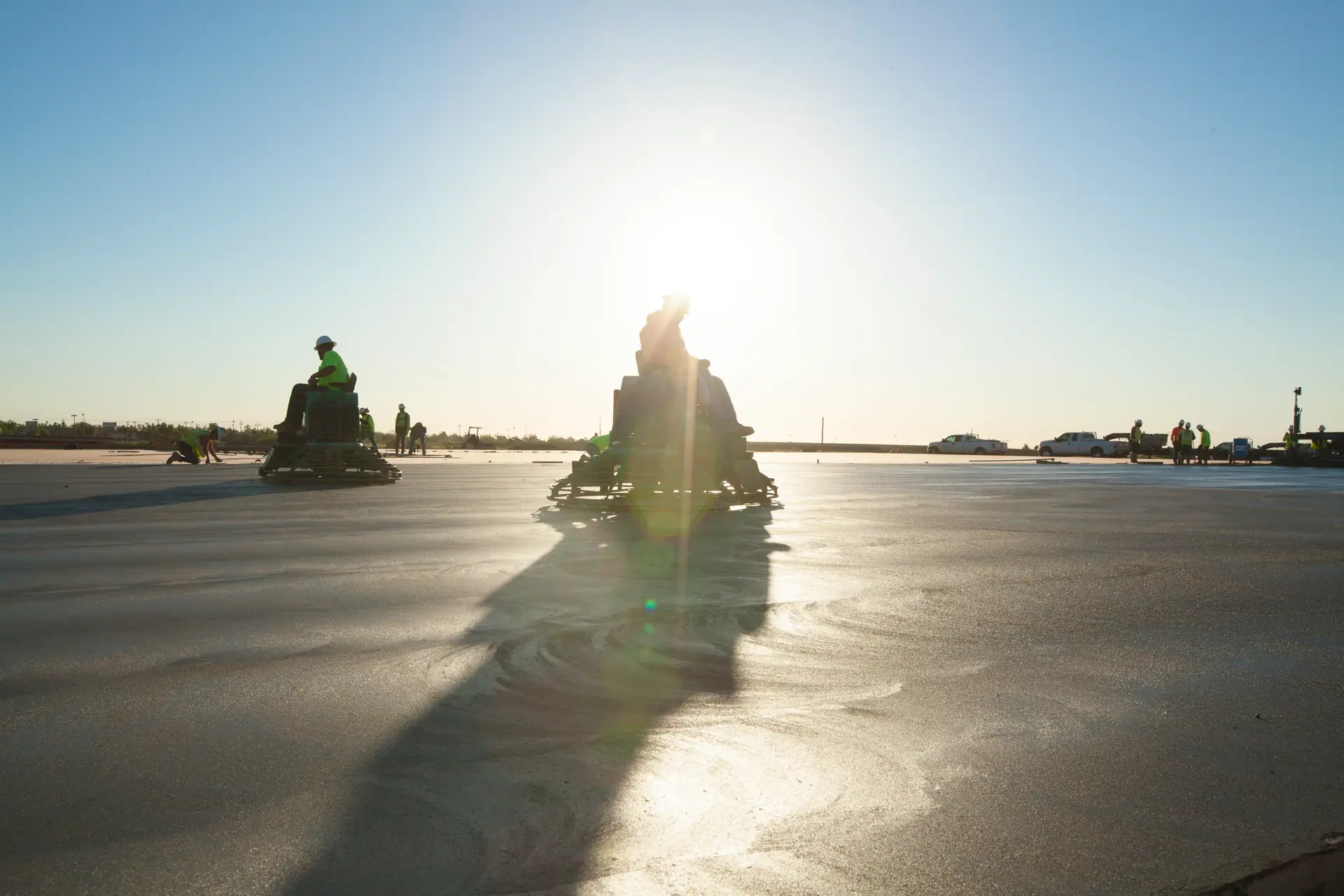Ride-on power trowels finishing a commercial concrete slab at sunset, Oklahoma